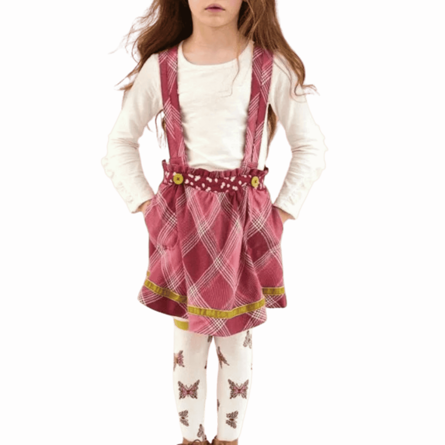 Child wearing a pink plaid dress with suspenders on a red background