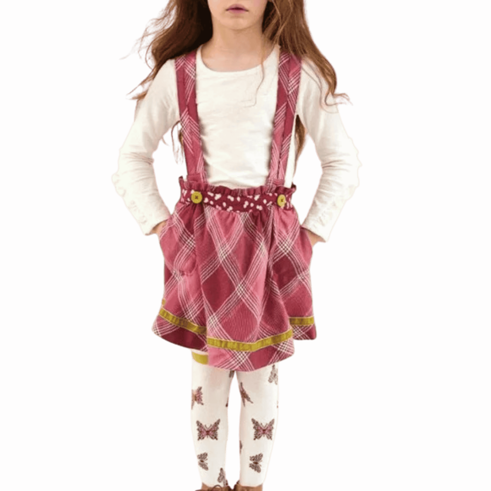Child wearing a pink plaid dress with suspenders on a red background