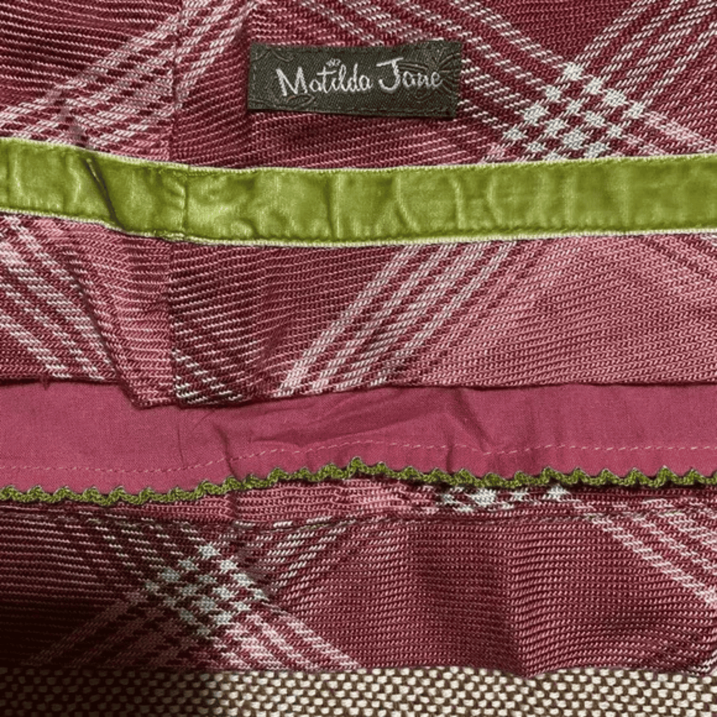 Close-up of a plaid fabric with a green trim and 'Matilda Jane' label.