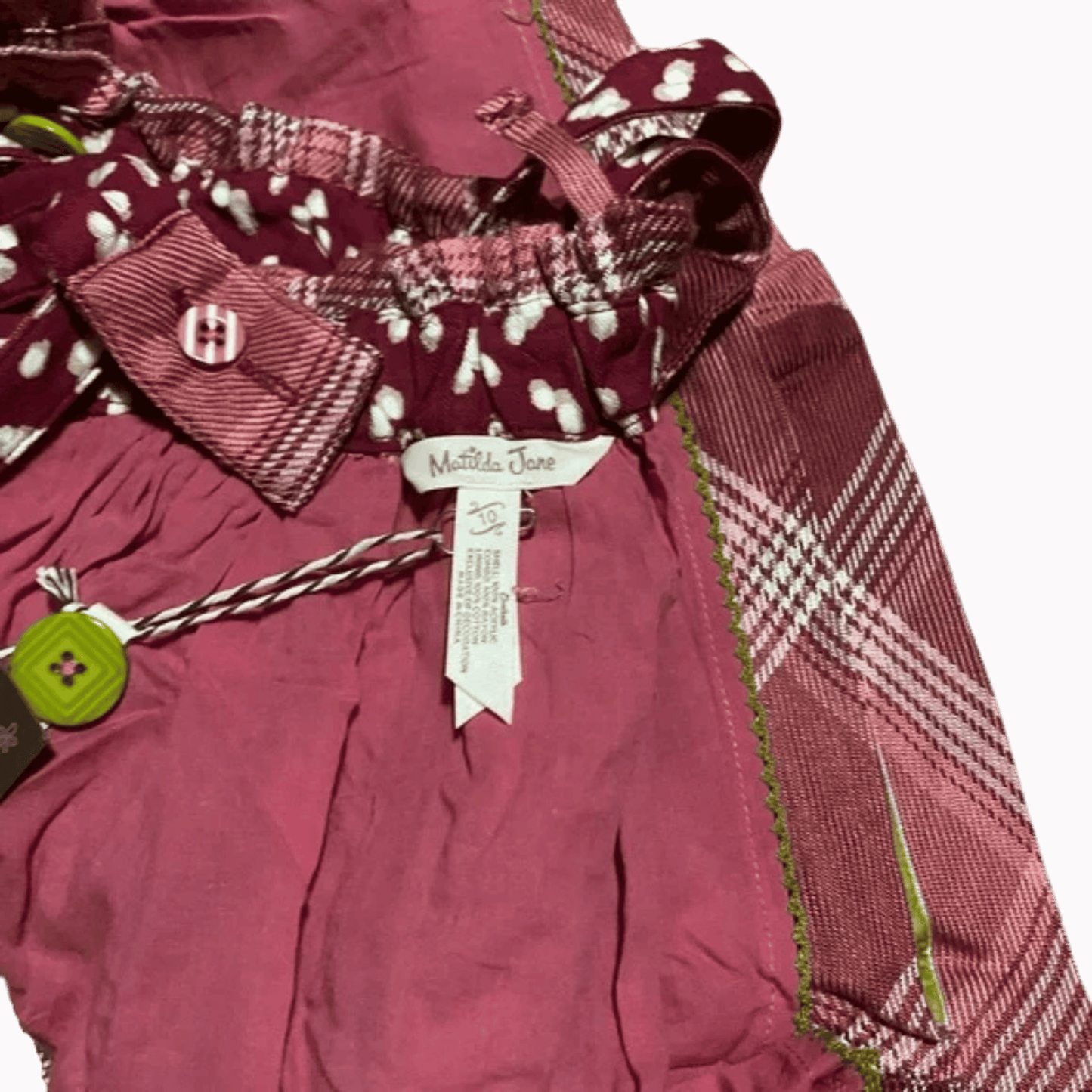 Maroon baby outfit with plaid pattern and visible brand tag on a brown background